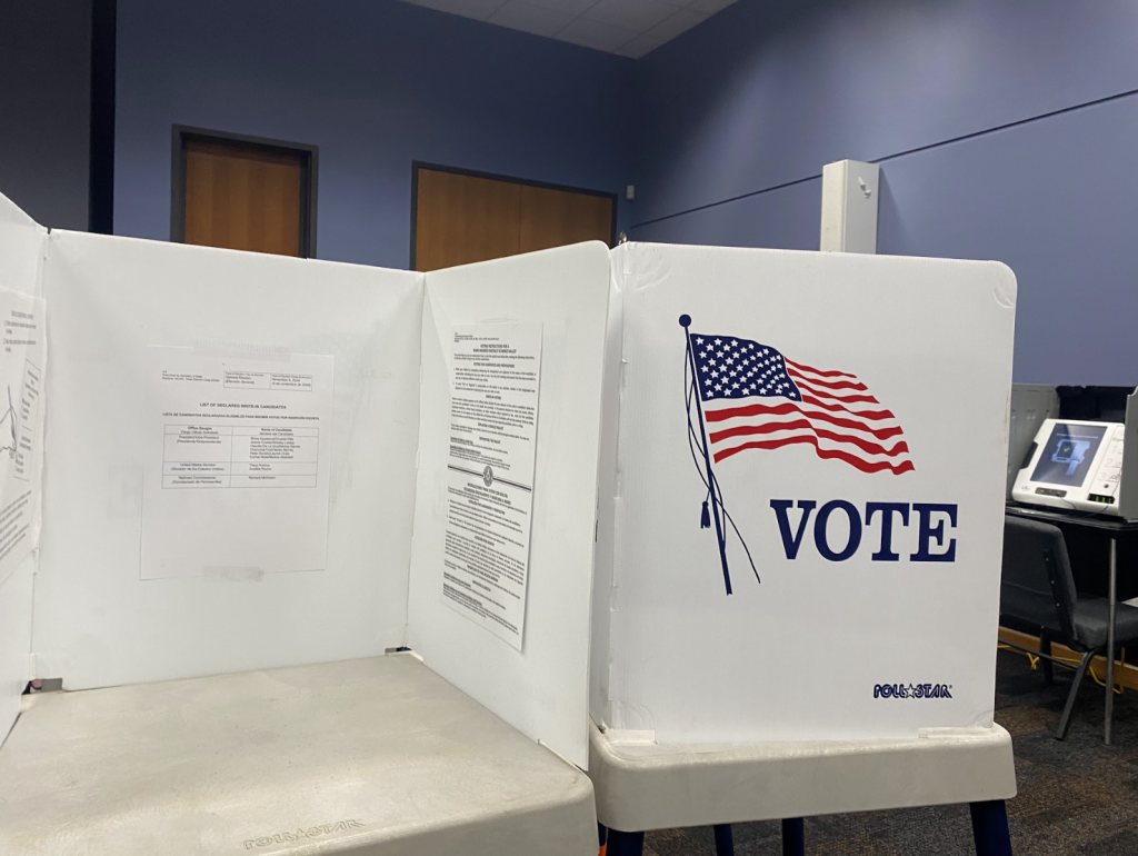 A table with white dividers; one divider has an American flag and the word VOTE above it.
